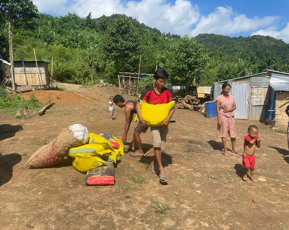 Christian refugee from Myanmar carrying a bag of rice